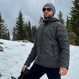 Мужчина в куртке цвета Raven на фоне заснеженного леса
